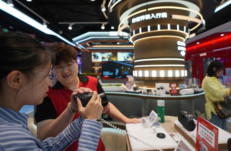 中国电商巨头京东近年来持续将海外布局扩大。图为大连京东MALL商场的销售专员向顾客推荐照相机。(新华社)