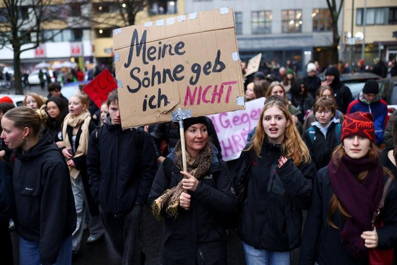 德国柏林的学生5日参加反对计划可能实施义务役制度的抗议时,展示一张海报,上面写着「义务役是倒退」。(美联社)