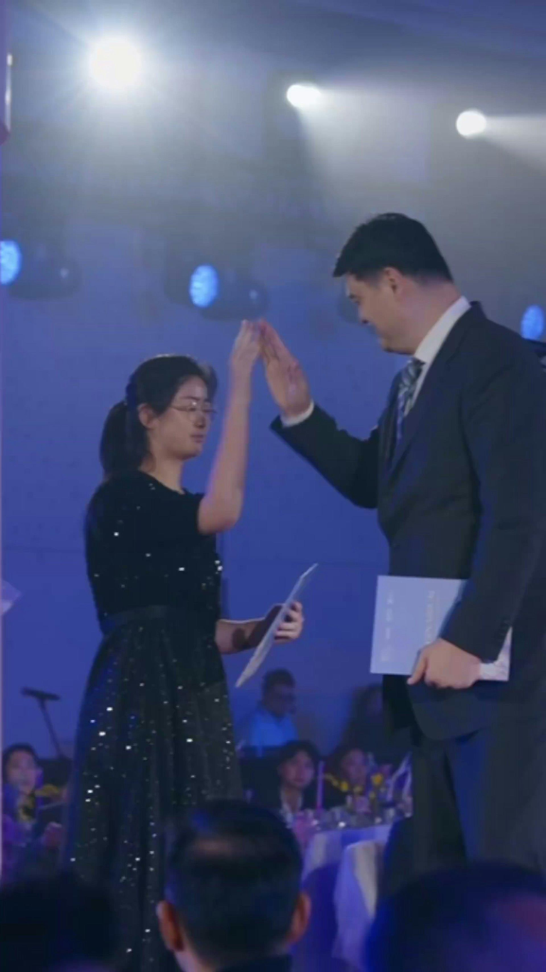姚明的「姚基金」近日在上海举行慈善晚宴，15岁女儿姚沁蕾为姚明担任现场翻译，影片中姚沁蕾身高已超过父亲肩膀。（取材自微博）