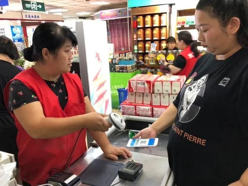 中国人民银行会同国家发展改革委、金融监管总局联合发布「人民币现金收付及服务规定」,明确自2026年2月1日起,行政机关、事业单位、公共服务机构及各类经营主体,不得随意拒收人民币现金,不得对现金支付采取歧视性措施。图为北京民众在超市结帐向店员出示支付宝。(本报数据照片)