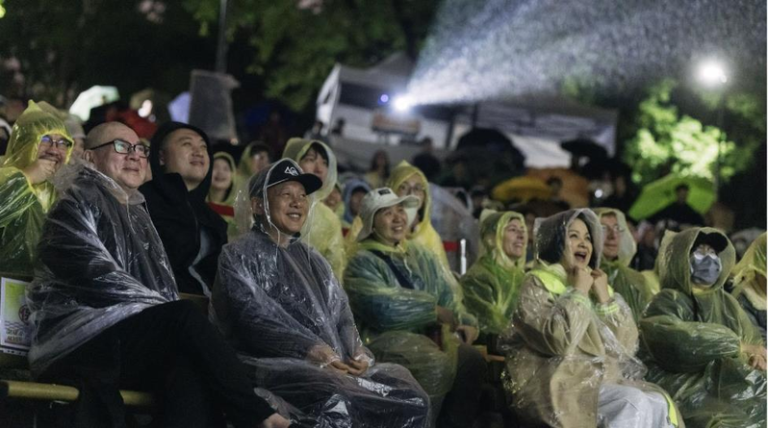 千人冒雨「边哭边跨年」 蔡明亮一段话惹哭现场 「爱情万岁」导演蔡明亮、李康生、杨贵媚穿着雨衣准备和大家一起倒数。(国家影视听中心提供)