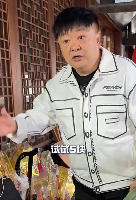 洪剑涛在浙江绍兴安昌古镇想试戴帽子,商家表示要收钱。(视频截屏)