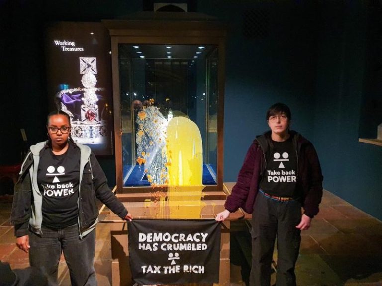 英社运人士闯伦敦塔 朝王冠展示柜丢食物喊「民主崩溃」 自称非暴力公民抵抗组织「夺回权力」6日发布照片显示,两名该组织支持者朝伦敦塔展示帝国王冠的展示柜砸食物,并拿着写了「民主已崩溃—对富人征税」的横幅。(路透)