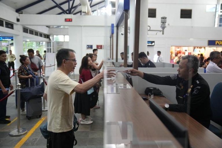图为新加坡海关人员将护照递还给一名旅客。(美联社)
