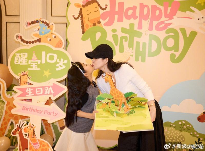 章子怡为女儿醒醒庆生,醒醒手上拿的是她出版的绘本「想变矮的长颈鹿」。(取材自微博)」