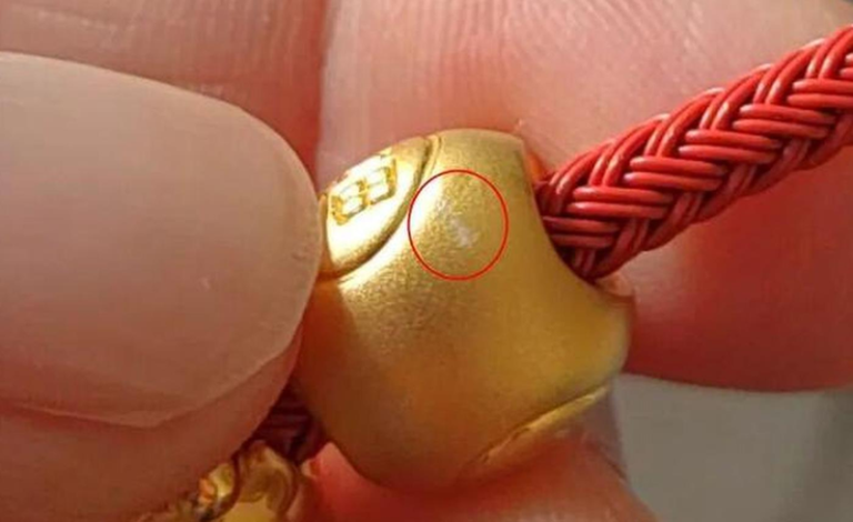 照片显示，坠饰刮花位置出现白色痕迹。(取材自央广网)