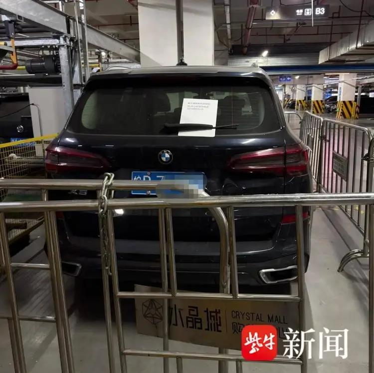 杭州水晶城商场将停车场里一辆积欠停车费的黑色宝马X5围栏围起来「锁住」。(取材自紫牛新闻)