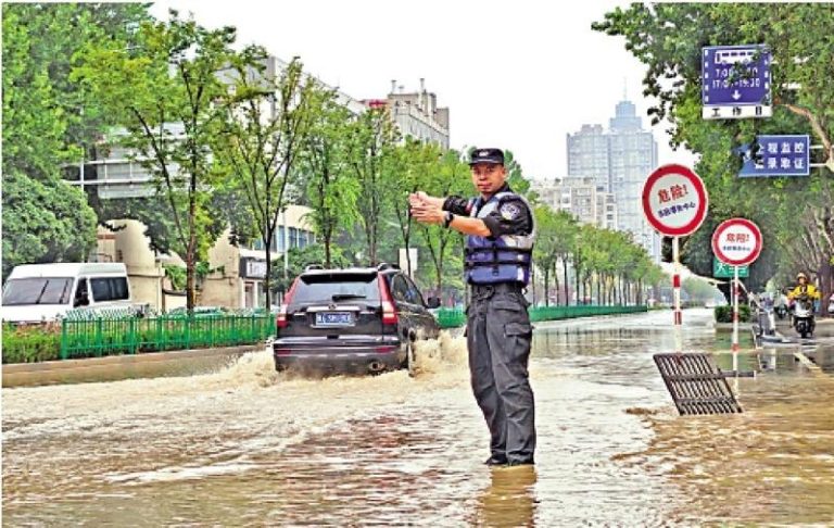 去年9月河南郑州出现局部暴雨。图为交警在积水路段指挥交通。（中新社）