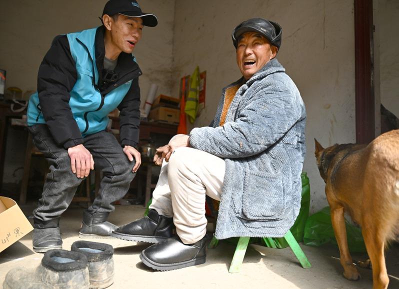 马高杰(左)把年货拿给村民。(新华社)