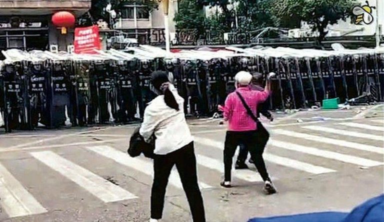 火葬场选址近民宅 茂名爆冲突 白发奶奶向警扔石头暴红 大批村民前日在信宜市政府门口示威抗议,数百名手持盾牌、警棍的防暴警察列阵。其间,一名满头白发的婆婆上前,连续向防暴警扔石块,这一画面在网上广传。(视频截屏)