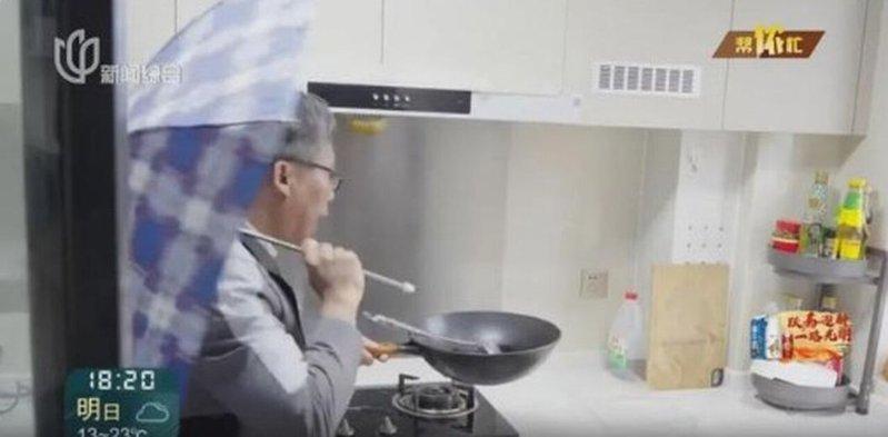 但先生打伞做饭。(取材自新闻坊)