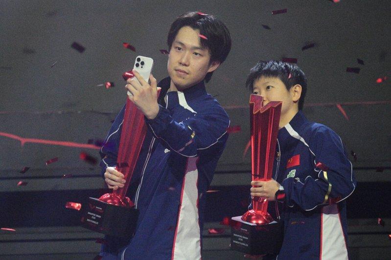 男单冠军王楚钦(左)和女单冠军孙颖莎在颁奖仪式上自拍合影。(新华社)
