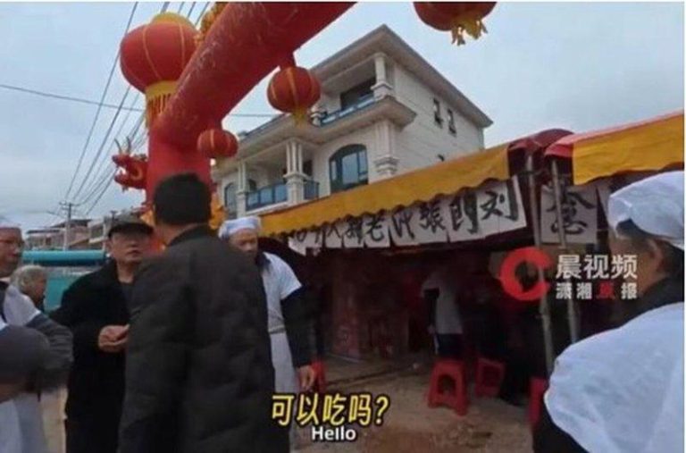 两名美国人骑乘摩托车游中国，经湖南时误闯一户正在举办白事酒席的人家，两人当时饥肠...