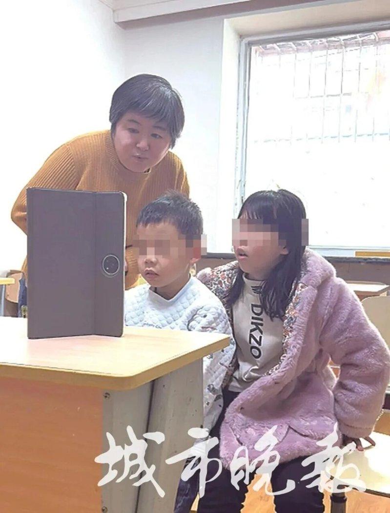 赵瑾拿学习机给两个孩子播放西游记的故事。(取材自城市晚报)