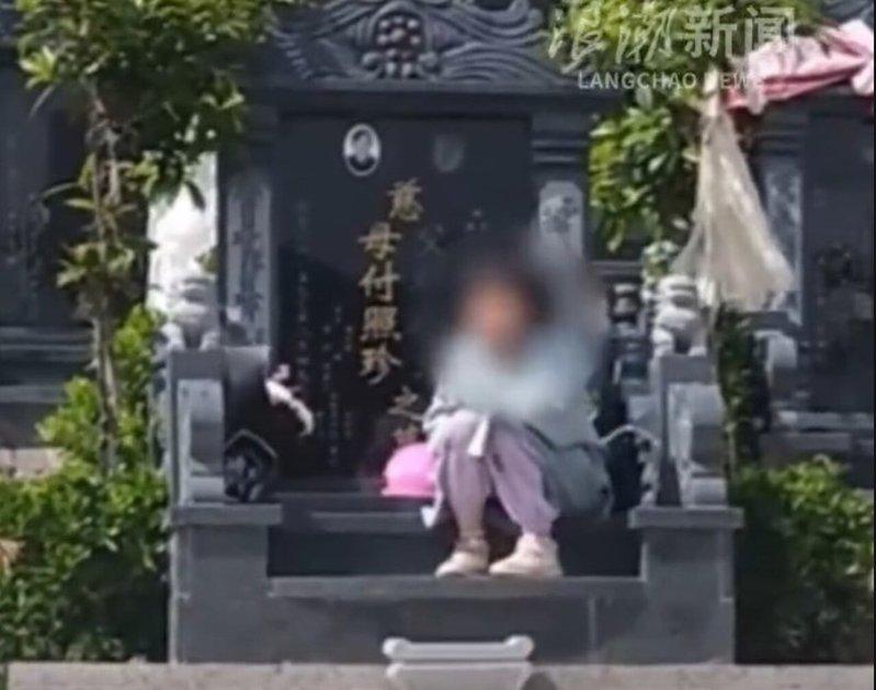 女孩靠在外公外婆的墓前。(视频截屏)