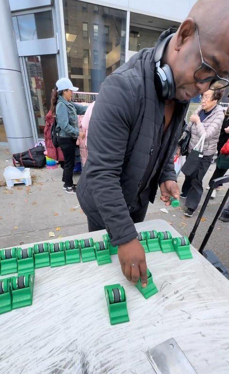 一名河南男子在洛杉矶摆摊卖磨刀器、老花镜等中国生产小对象,周末生意好时一天能赚5...