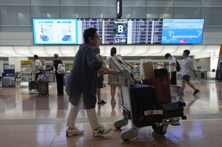 羽田机场一周两度遇系统故障 国际线改人工办理登机手续 日本东京羽田机场的乘客们正在查看航班资讯。(美联社)