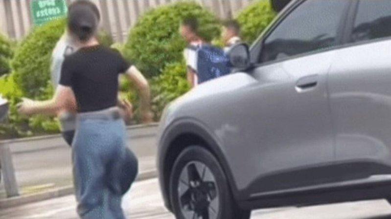 女司机下车后脚踹男保安(图),被保安反手搧了一耳光。(视频截屏)