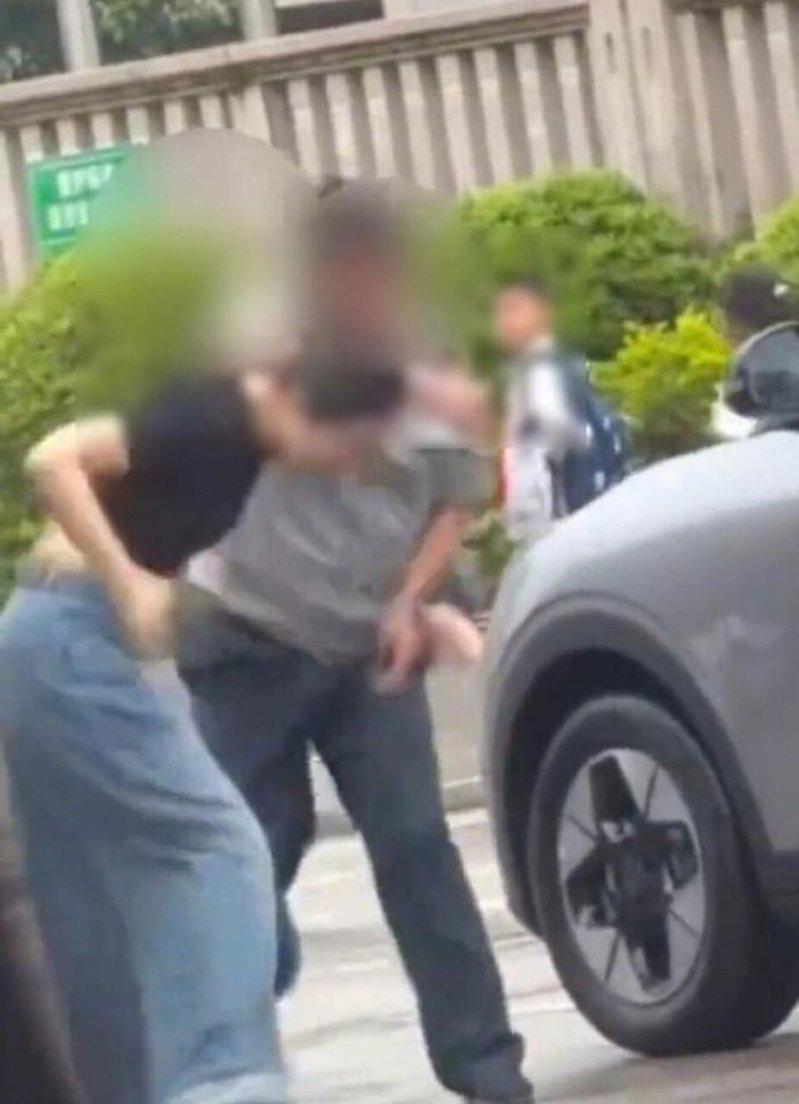 女司机下车后脚踹男保安,被保安反手搧了一耳光(图)。(视频截屏)