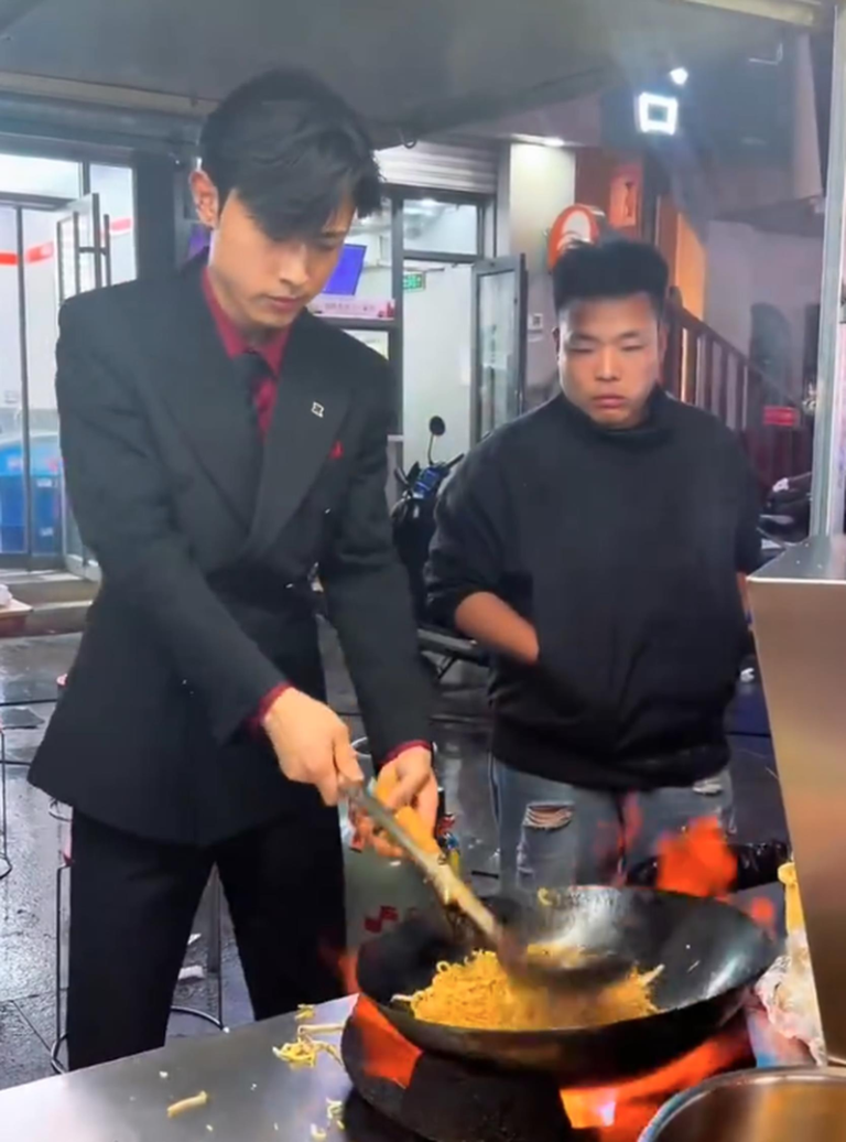 山东烟台一名19岁小伙因身着西装在夜市摆摊卖炒饭走红网络。(视频截屏)