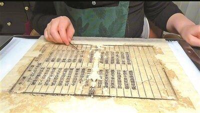 用小镊子去掉古籍纸页上的碎渣。(取材自北京青年报)