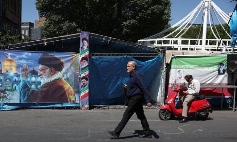 伊朗:与美国在许多议题取得共识 但不会很快达成协议 一名男子25日走过伊朗德黑兰街头纪念已故最高领袖哈米尼的横幅。(路透)