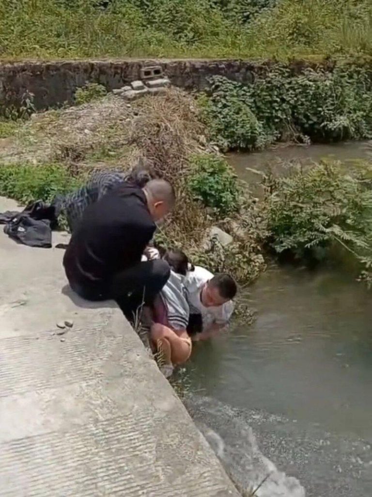 女孩落水被卡桥洞冲掉裤子，男子在水中帮女孩穿好衣物被质疑行为不妥。（视频截屏）