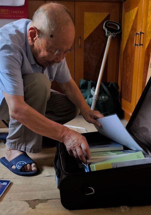 林宝山在清理行李箱里的书。(取材自潇湘晨报)