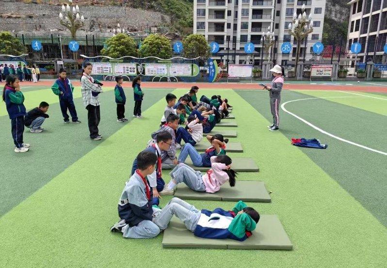 西湖小学学生在操场进行仰卧起坐。(新华社)
