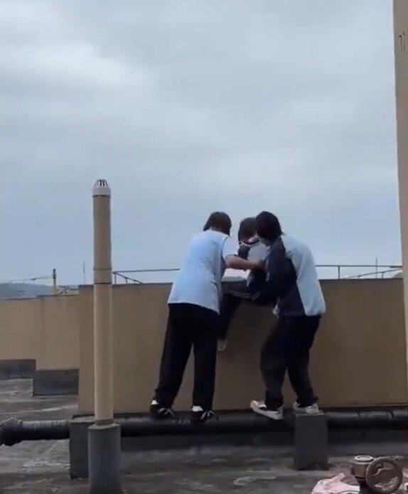 两名疑似欺凌者的女生与另一女生在大台边缘纠缠。(视频截屏)