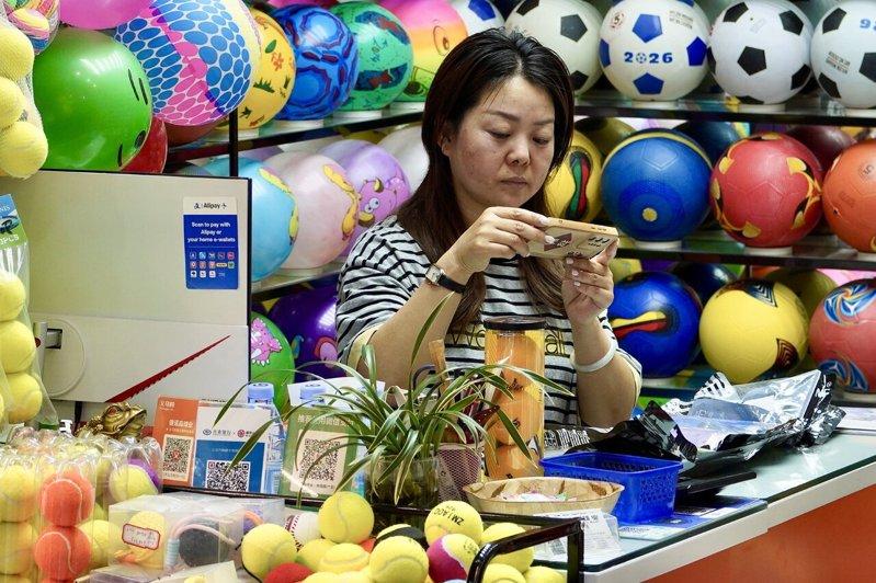 店舖负责人给在线客户拍摄足球护腿板样品照片。(中新社)