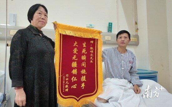 获张颂文救助的伤者(右)展示感谢锦旗。(取材自南方+客户端)