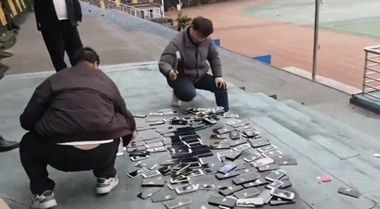 湖南一学校当众砸毁没收学生的上百部手机 网怒:带头违法 涉事学校老师拿铁槌将没收来的学生手机当众砸毁。(视频截屏)