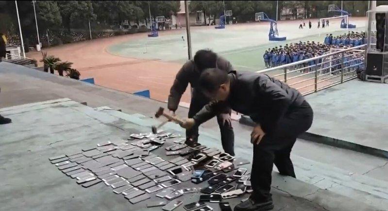 涉事学校老师拿铁槌将没收来的学生手机当众砸毁。(视频截屏)