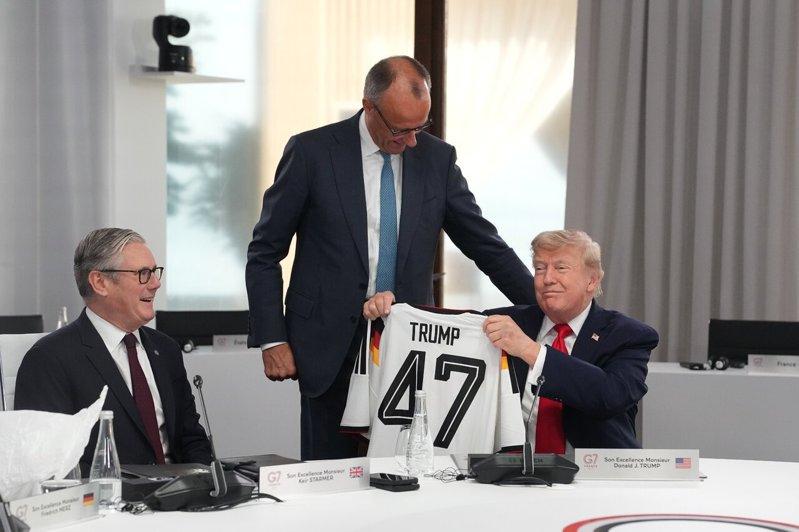 德国总理梅尔茨(中)在G7峰会上,将印有「47」号码的德国国家足球队球衣给美国总...