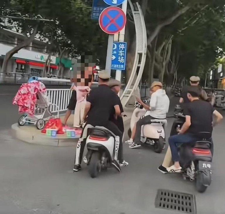 几位骑电动车小伙给在路边求助的父女扫码捐款。(取材自大象新闻)