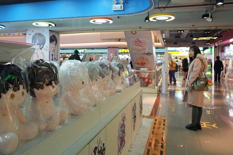 一名女玩家正看着广州一家商场里「恋与深空」角色的绒毛玩具。示意图。（路透）