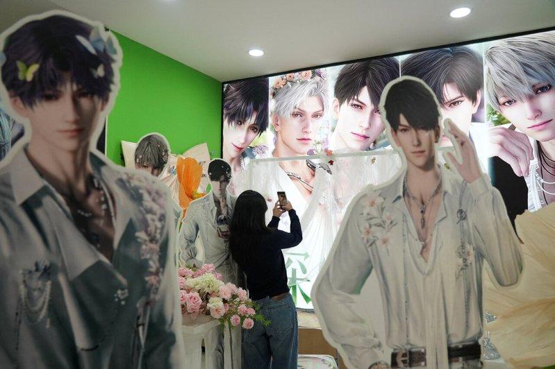 一名女子在商场内展示手游「恋与深空」角色形象的摊位旁拍照。（路透）