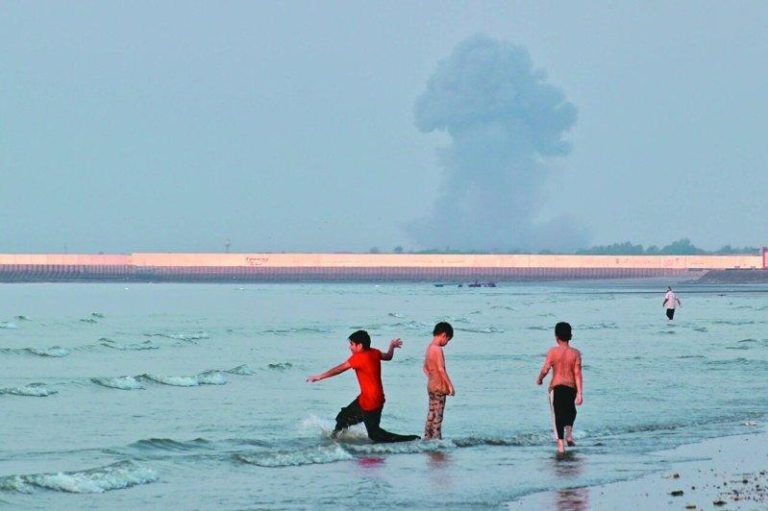 不只荷莫兹 伊朗威胁封锁红海曼德海峡 油价恐飙升200元 三名男孩13日在伊朗阿巴斯港外海的荷莫兹海峡浅水区玩耍,远处可见爆炸升起的烟柱。...