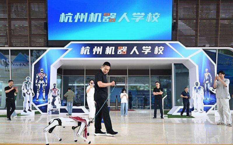 6月29日，浙江杭州，体验者在杭州机器人学校门口遛机器狗。 (中新社)