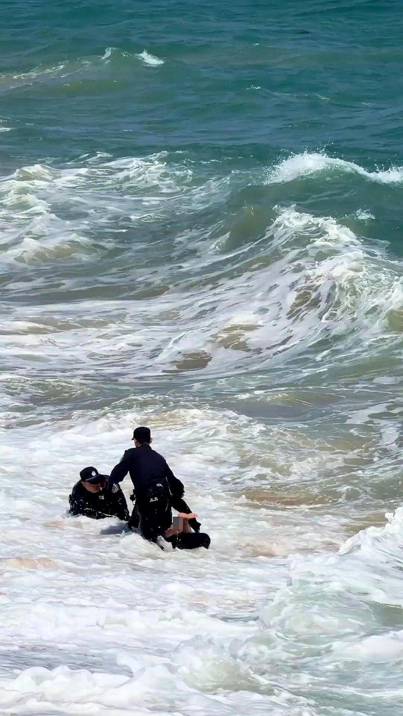 图为今年2月,在海南省陵水黎族自治县黎安镇的一处海边景点,3名警员冲入海中,救回...