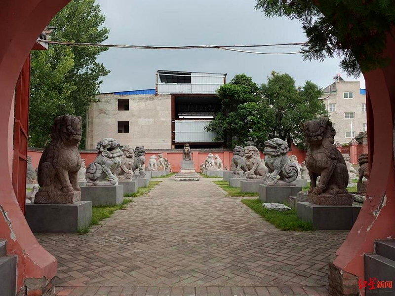 月洞门两侧各立着一尊颜色暗沉的石狮。(取材自红星)