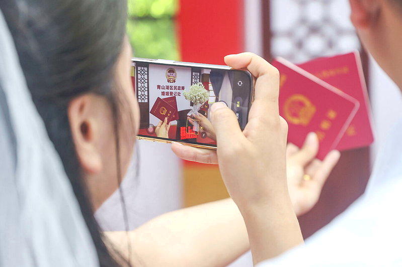 一对新人拿结婚证拍照。(中新社)