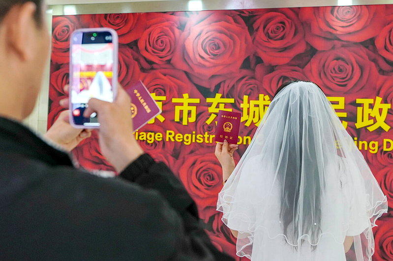 一对刚刚领证的新人在结婚登记处拍照留念。(新华社)