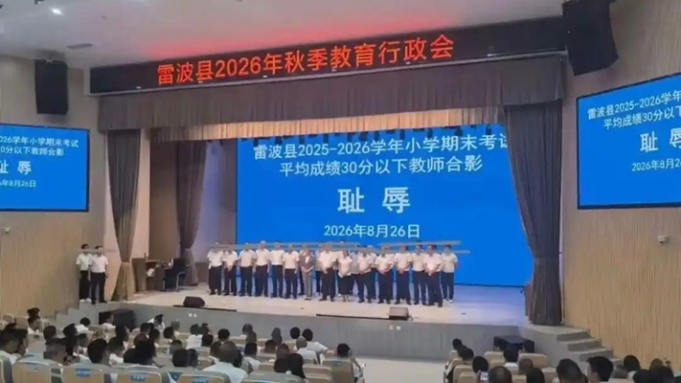 雷波县2026年秋季教育行政会，台上身著白衬衫和黑西裤的教师在「耻辱」二字的背影...