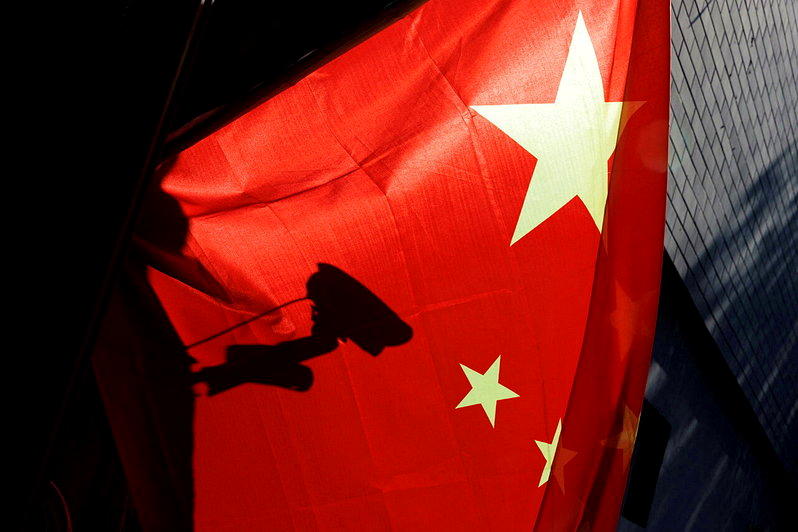 近年多家外媒指中国对人身自由的监控无所不在。图为一面中国五星旗后方，一个监视器的...