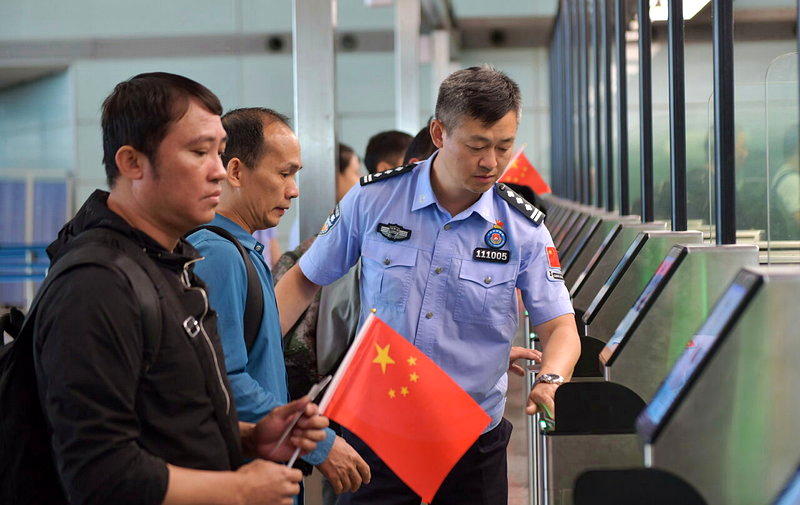 图为北京出入境边境检查总站的一名警员在北京首都国际机场协助中国公民办理入境手续。...