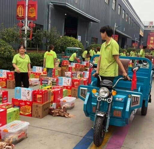 江苏徐州一家机车企业向每名员工发放26种中秋礼品,员工们正将奖品装上三轮车带回家...
