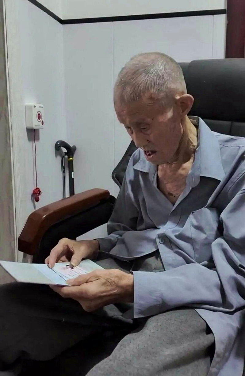 张中义查看新办下来的身分证和户口簿。(取材自封面新闻)