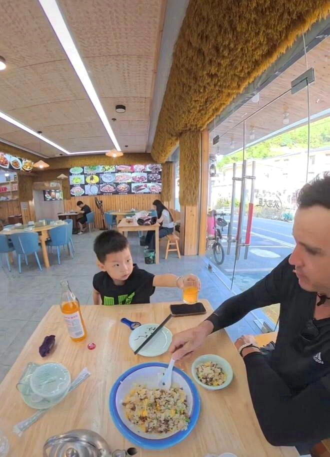 孩子给游客倒上饮料,亲自递到他手边。(取材自九派新闻)